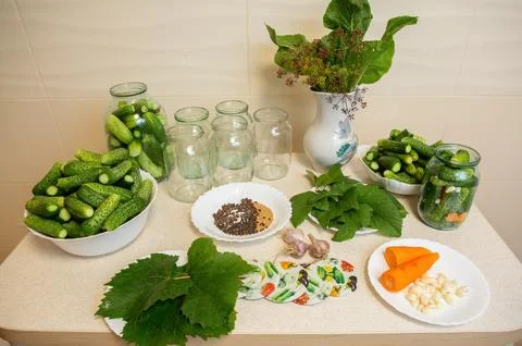 On the table are cucumbers prepared for canning, jars, and carrots, garlic,.. Stock Photos