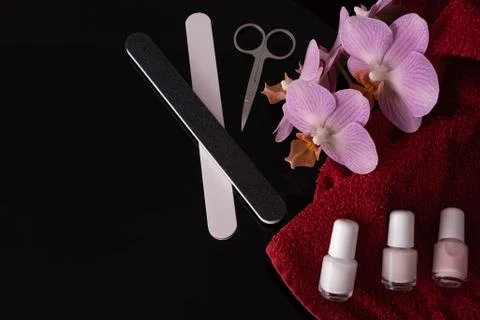 On the table are nail files, a pink orchid, a towel and nail scissors Stock Photos