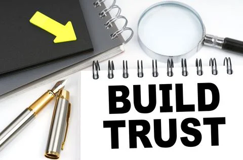 On the table are a pen and a notebook with the inscriptions - Build trust Stock Photos