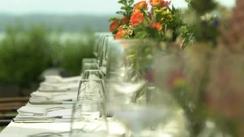 Table arrangement with empty wine-glasses and flowers in natural garden colors Stock Footage 248379346