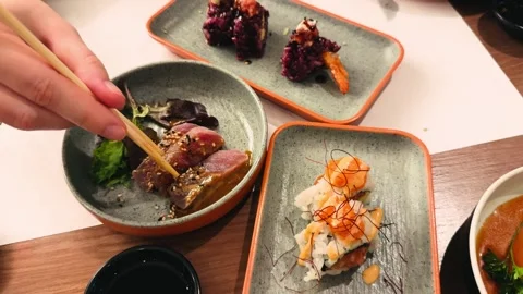 On the table at an Asian restaurant are dishes of fresh tuna, shrimp, and salmon Stock Footage 335760653