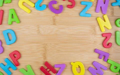 Table background with wood texture with lots of colorful letters around the e Stock Photos