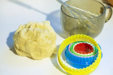 On the table is a baking dough cookie pan and a whisk. Cookies making process Stock Photos