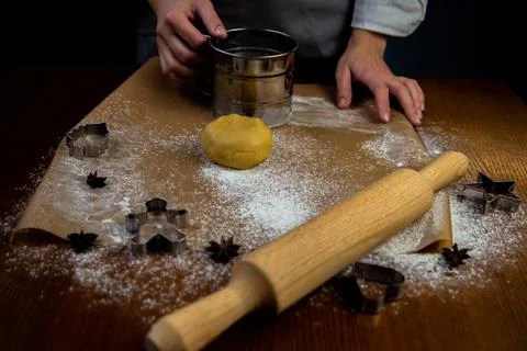 A table with baking parchment lying on it, scattered flour, rolling pin, dough Stock Photos