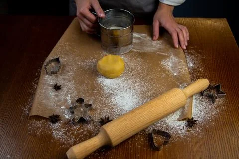 A table with baking parchment lying on it, scattered flour, rolling pin, dough Foto stock