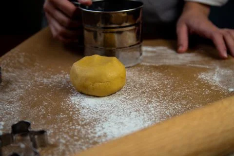 A table with baking parchment lying on it, scattered flour, rolling pin, dough Foto stock