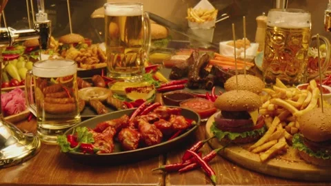 Table with beer fast food fried fries chicken wings burgers sausages , sauces Stock Footage 213580005