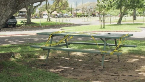 Table bench at beach park closed blocked with yellow caution tape, coronavirus. Stock Footage 133822457