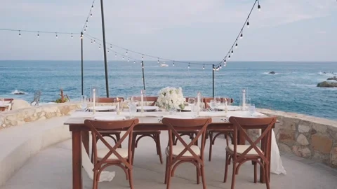 Table with a bouquet of white roses, wine glasses, plates and candles by the sea Stock-Footage 280445973