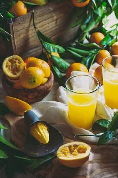 Table with box of fresh orange with orange tree branch and fresh orange juice Stock Photos