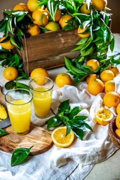 Table with box of fresh orange with orange tree branch and fresh orange juice Stock Photos