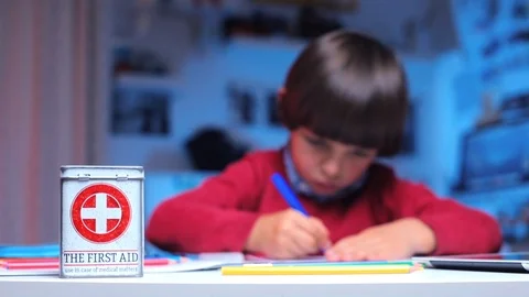 On the table is a box with the inscription first aid, on the background of a boy Stock Footage 116536337