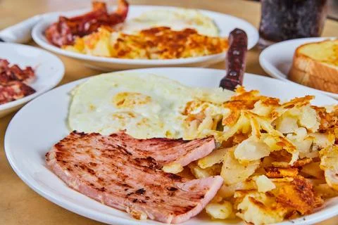 Table of breakfast with focus on ham, potatoes, and eggs Foto stock