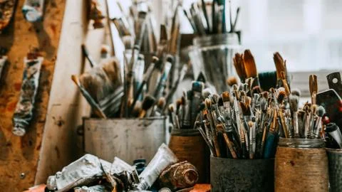 Table with brushes and tools in art workshop. Background. Stock Photos