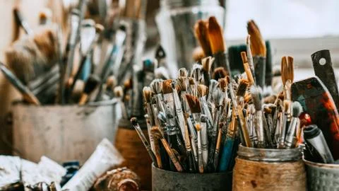 Table with brushes and tools in art workshop. Background. Stock Photos