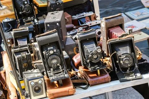 A table with a bunch of old cameras and a gun Stock Photos