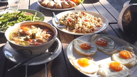 A table in a cafe covered with sunshine is covered with Thai food, the camera Stock Footage 88730166