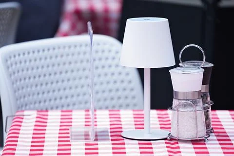 Table in cafe covered tablecloth with white desk lamp, salt and pepper Stock Photos