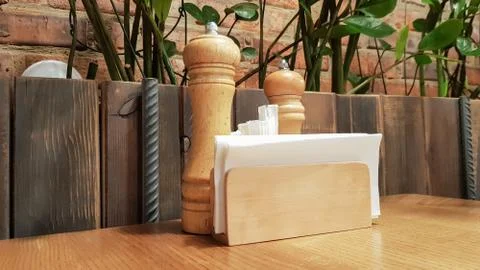 A table in a cafe or restaurant. White napkins in a wooden holder, salt and p 写真素材