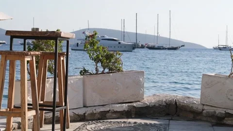 A table in a cafe by the sea. In the background a yacht and sailing ships Stock Footage 221986572