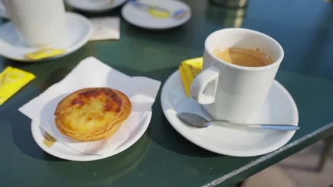 Table in cafe shop with coffee cup and famous Portuguese Pastel de Nata sweet Stock Footage 289677653