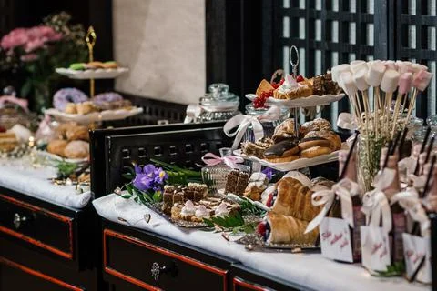 Table with cakes and various snacks, and small bottles of sparkling wine at the  Stock Photos