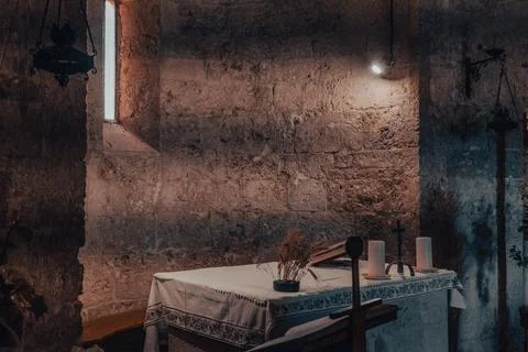 Table with candles in a small ancient medieval stone chapel 스톡 사진