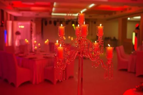 On the table is a candlestick made of crystal with white candles. Decoratio.. Stock Photos