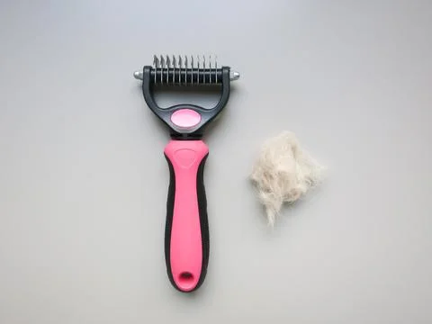 On the table is a cat's comb and a tuft of hair. Stock Photos