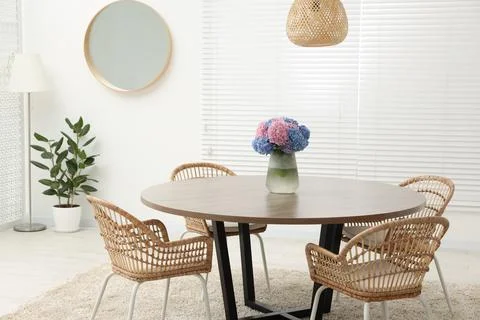 Table, chairs and vase of hydrangea flowers in dining room. Stylish interior Stock Photos