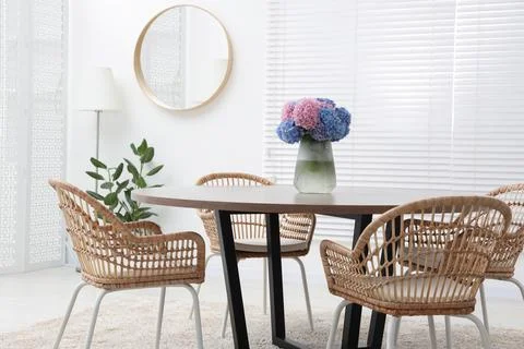 Table, chairs and vase of hydrangea flowers in dining room. Stylish interior Stock Photos