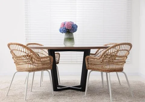 Table, chairs and vase of hydrangea flowers in dining room. Stylish interior Stock Photos