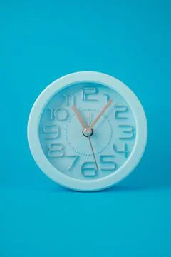 Table clock in the middle of the image, isolated on a light blue background Illustration