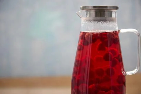 On the table cools a carafe with hot drink of freshly frozen berries with sugar Foto stock
