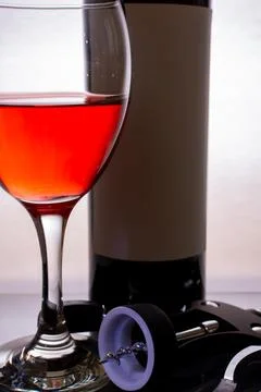 On the table is a corkscrew, a bottle of wine and vocals with wine Stock Photos
