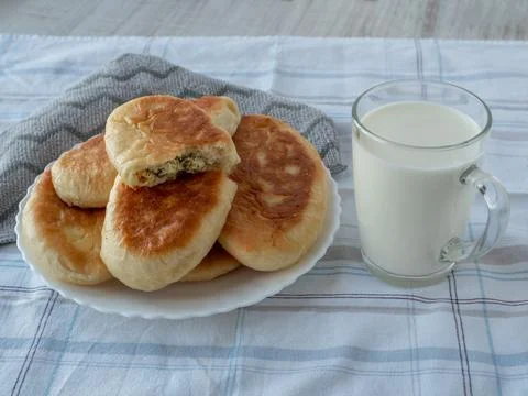 On table, covered with gray tablecloth, there is glass of fresh milk and plate Stock Photos