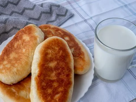 On table, covered with gray tablecloth, there is glass of fresh milk and plate Stock Photos