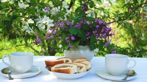 On a table covered with a white tablecloth, cups with saucers, sliced buns and a Stock Footage 237683248