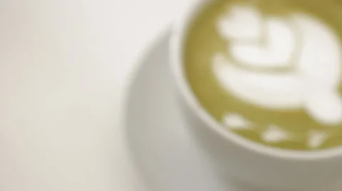 On the table is a cup of coffee with foam and pattern and girl takes photo of Stock Footage 67529885