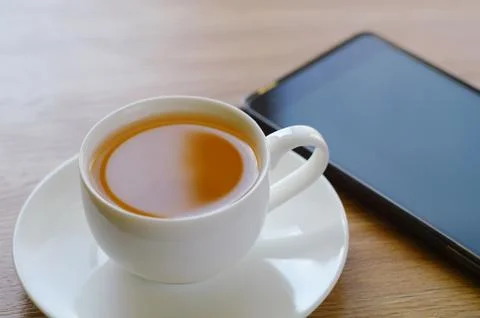 On a table a cup of tea and the smart phone. Stock Photos