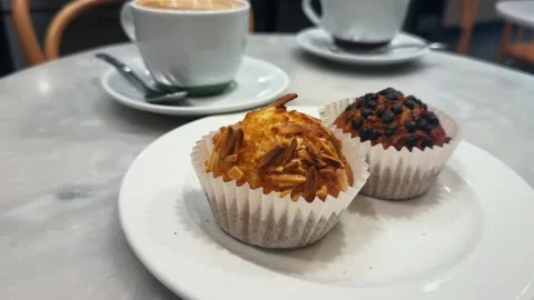 Table with cupcakes and steaming coffee at a cafe. Stock Footage 297760498