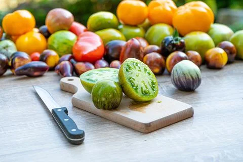 Table with a cutting board with sliced tomatoes and different colored tomatoe Stock Photos