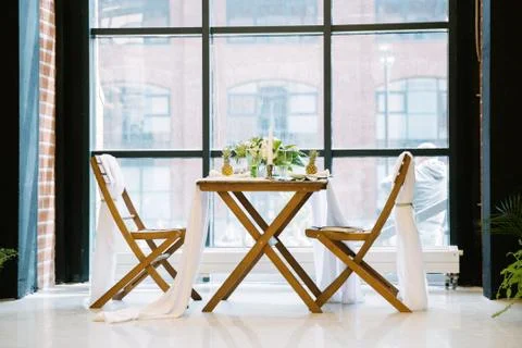 Table decorated with plates, pineapples, candles and flowers, green and white Stock Photos