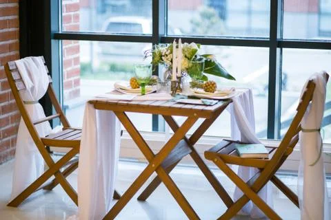 Table decorated with plates, pineapples, candles and flowers, green and white 库存照片