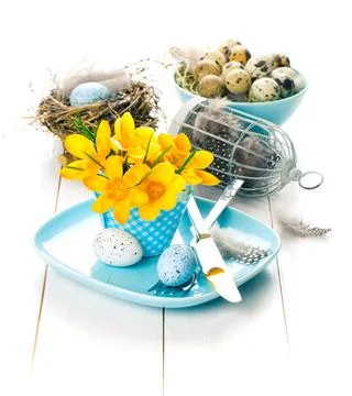 Table decoration with easter eggs nest on plate, on white wooden background Stock Photos