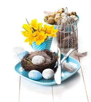 Table decoration with easter eggs nest on plate, on white wooden background Stock Photos