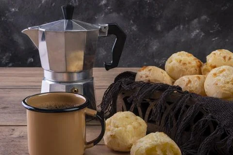 Table with delicious cheese breads, a coffee mug and a traditional coffee mak Stock Photos