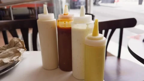 On the table in the diner there are bottles with various sauces such as mustard Stock Footage 327854993