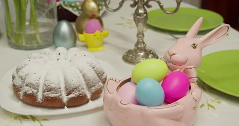 Table for the Easter holiday. a pink rabbit-shaped plate with painted eggs, a Stock Footage 172363991