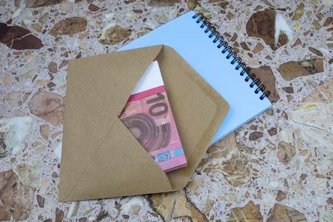 On the table is an envelope with a bundle of 10 euro banknotes and a notebook Stock Photos